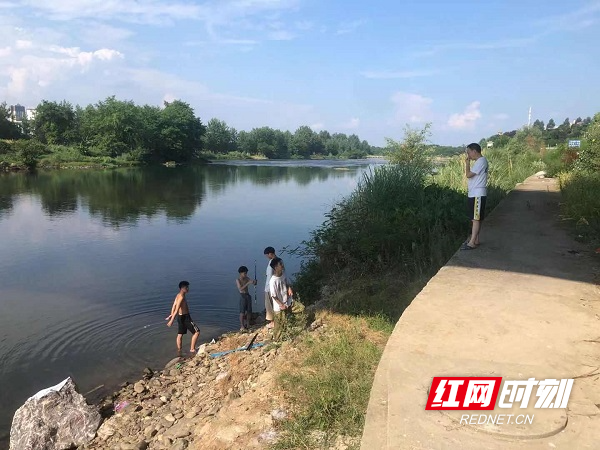 校长谢建波正在劝阻河边玩耍的小孩.jpg