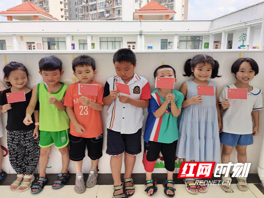 临武县幼儿园的孩子们高兴地与自己制作的五星红旗合影留念。.png