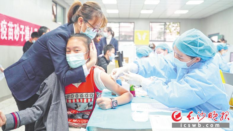 　　老师用双手护住正在接种新冠疫苗的学生，安抚其紧张情绪。　　长沙晚报全媒体记者 易亿 摄