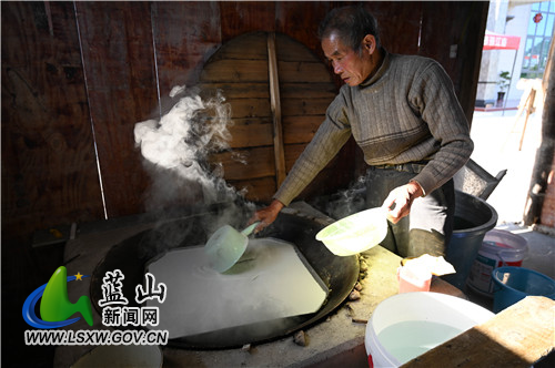 图三：2021年11年25日，湖南省蓝山县塔峰镇糯江村，黄英义在将红薯浆放入大锅中蒸.jpg