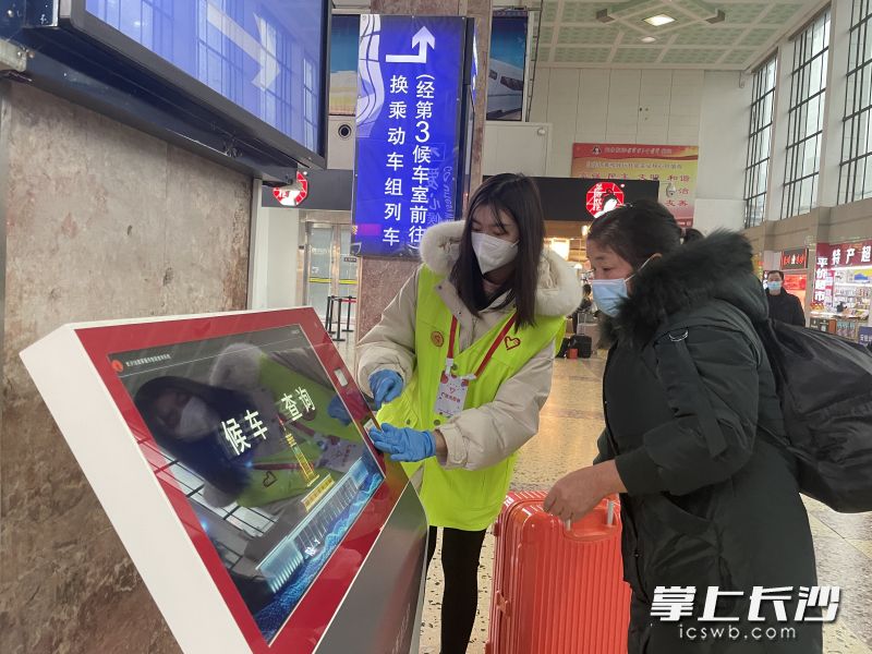 在长沙火车站，大学生志愿者正在协助旅客查询候车信息。