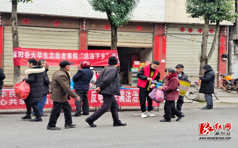 图为普法志愿者在集市摆摊设点为过往群众发放宣传资料.jpg