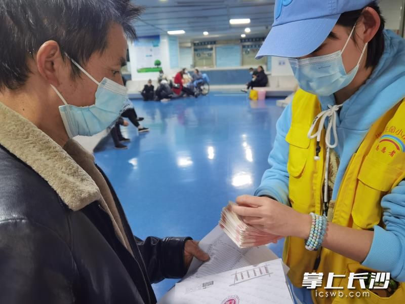 护士刘心把爱心款转交给小乐的父亲。