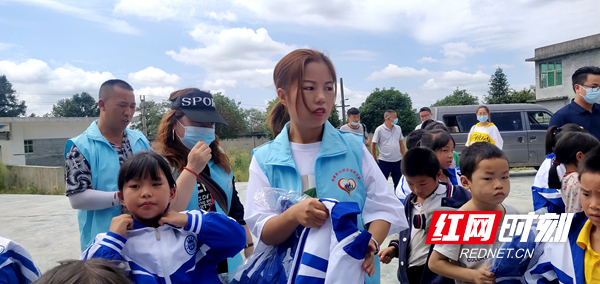 王燕在给孩子们分发新校服。.jpg 王燕在给孩子们分发新校服。.jpg