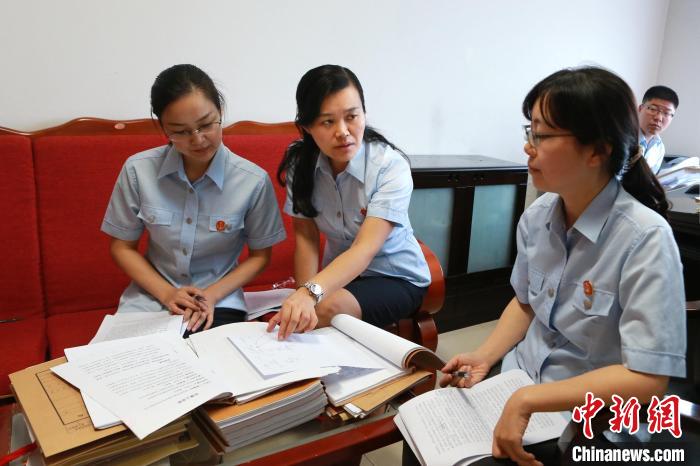 图为周春梅(左二)在和同事们交流工作。　湖南省高级人民法院供图
