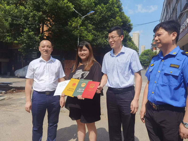 7月11日下午，望城区住建局、望城区规划局负责人将《农村宅基地批准书》《建设工程规划许可证》《建设用地规划许可证》和《建筑工程施工许可证》送到高塘岭街道莲湖社区居民刘宇欣手上，让她欣喜不已。 全媒体记者 朱华 摄