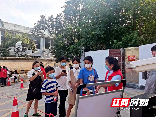 教师志愿者引导学生扫码进入学校。.jpg