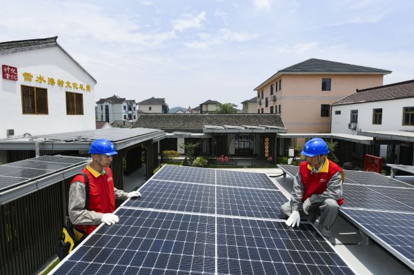 6月9日，在浙江嘉兴，工人们在村庄屋顶上安装光伏发电板。（新华社发）