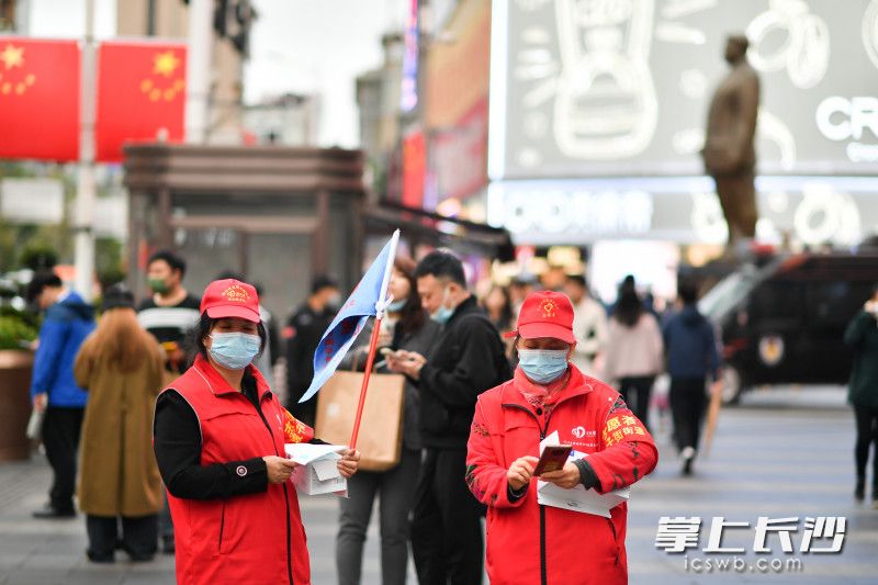 黄兴路步行街，坡子街街道志愿者给游客发放口罩。