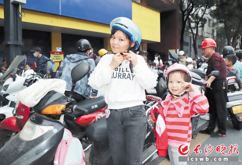 　　在开福区四方坪二小校门口，一名家长准备骑车送孩子回家。