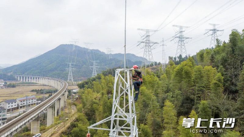 施工人员攀爬在铁塔上忙着将线路联通。