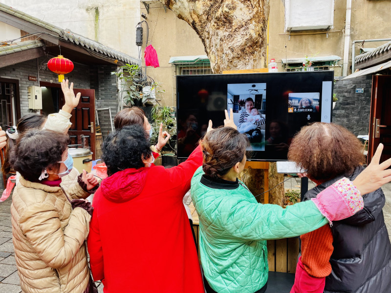 遠(yuǎn)在北京的袁娭毑抱著小外孫女，驚喜地和老街坊們隔空“云”團圓。