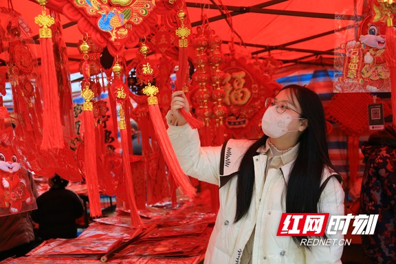 1月15日，春节临近，在湖南省靖州苗族侗族自治县的年货一条街，只见人来人往，琳琅满目的春节用品更是让人目不暇接，年味十足。图为一名顾客在认真挑选中国结。易子明+摄+(2).marked.jpg