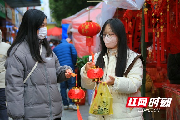 1月15日，春节临近，在湖南省靖州苗族侗族自治县的年货一条街，只见人来人往，而琳琅满目的春节用品更是让人目不暇接，年味十足。图为两名女孩一人提着一个漂亮的电子灯笼。易子明+摄.marked.jpg