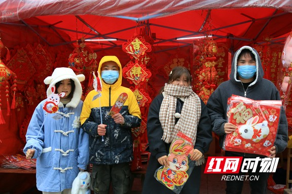 1月15日，春节临近，在湖南省靖州苗族侗族自治县的年货一条街，只见人来人往，而琳琅满目的春节用品更是让人目不暇接，年味十足。图为几名顾客各自挑选到心怡的商品后，在年货摊前合影留念。易子明+摄.marked.jpg