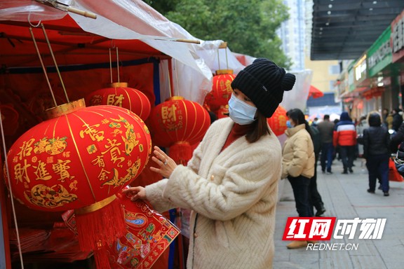 1月15日，春节临近，在湖南省靖州苗族侗族自治县的年货一条街，只见人来人往，而琳琅满目的春节用品更是让人目不暇接，年味十足。图为年货摊前，一名顾客正在选购灯笼。易子明+摄.marked.jpg