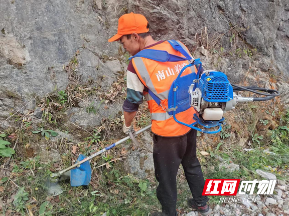 南山坪乡养护队队员唐国祥正在用割草机除草。.marked.png