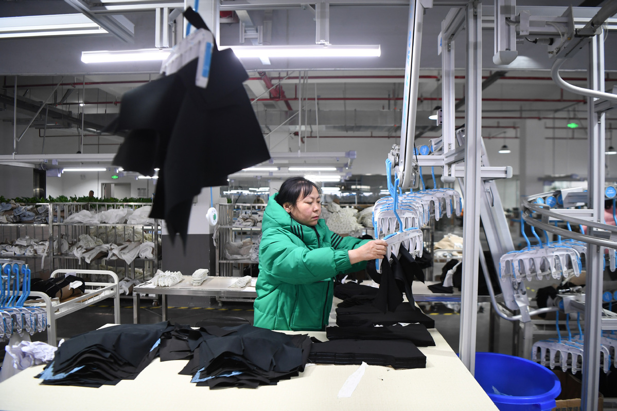 A worker produces clothes at a workshop in Zhuzhou, Hunan province, on Feb 15. [Photo/Xinhua]