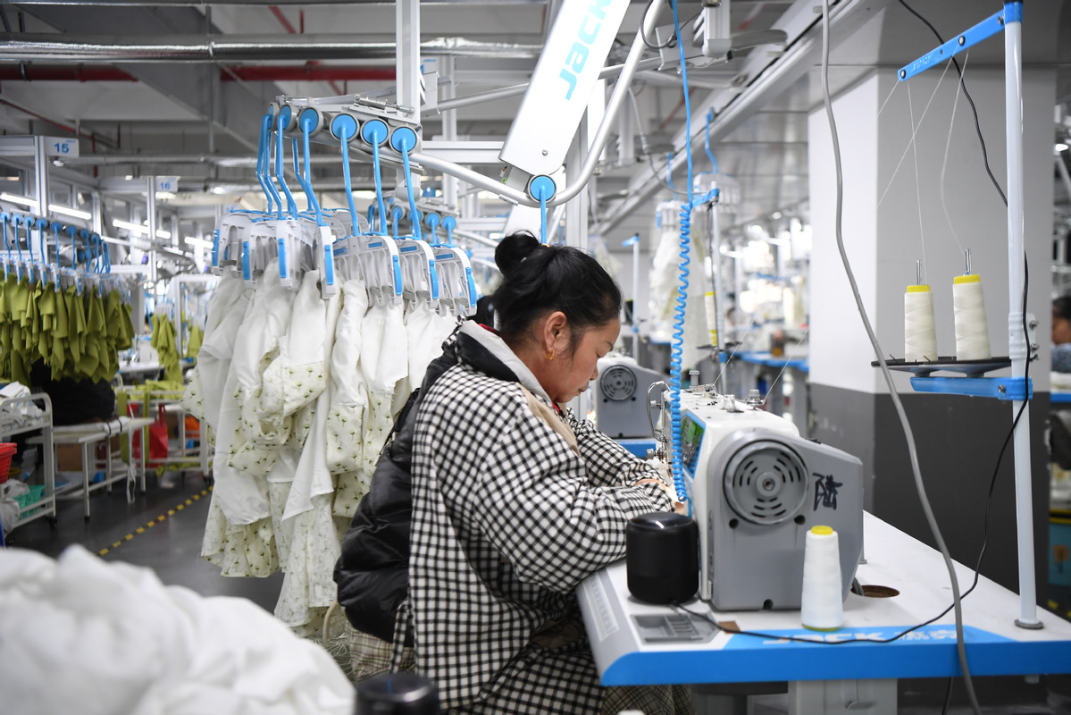 A worker produces clothes at a workshop in Zhuzhou, Hunan province, on Feb 15. [Photo/Xinhua]