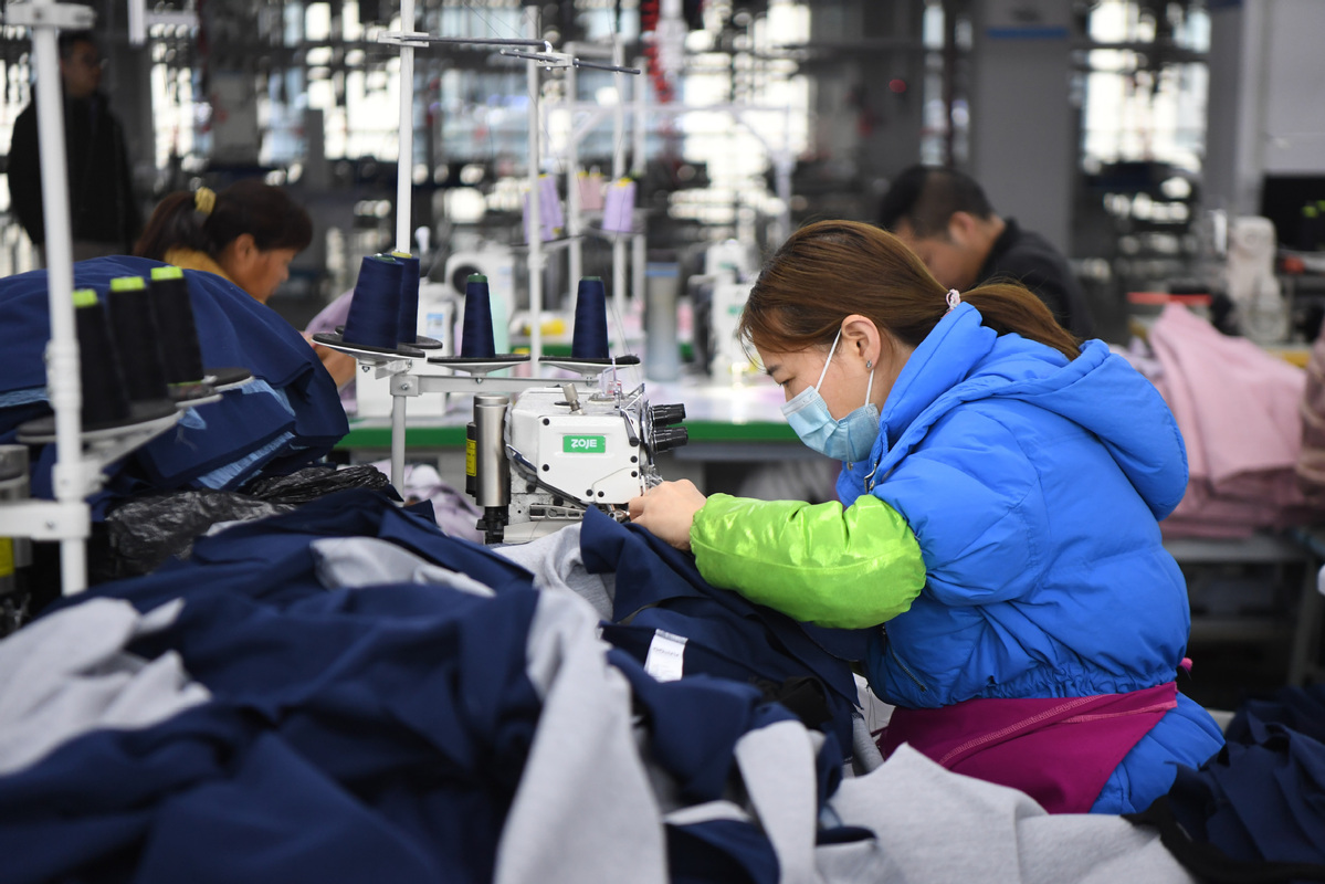 Workers produce clothes at a workshop in Zhuzhou, Hunan province, on Feb 15. [Photo/Xinhua]