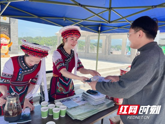 明旅游的带动地也引来不少外地游客，这位客人是从云南大理过来这边旅游，看到有志愿者服务，顺便来询问桑植有哪些好玩的景点，站长胡明明正在用桑植旅游手绘图册为她做解答！_副本.jpg