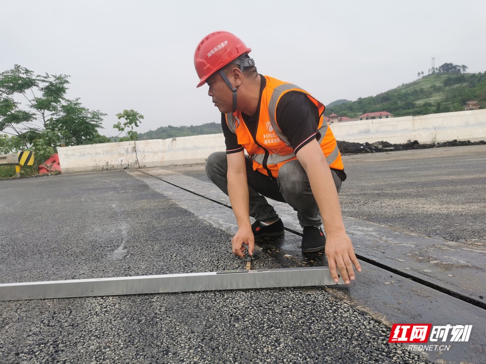 邓炜在施工现场测量路面平整度.jpg