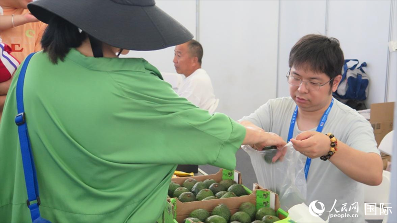 游客在中非经贸博览会上购买肯尼亚牛油果。人民网 宋歌摄