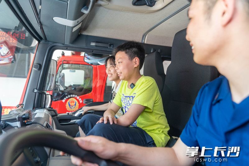 在驾驶员邹定乾的带领下，姐弟俩坐上当时他们为之领路的消防车，止不住露出笑容。
