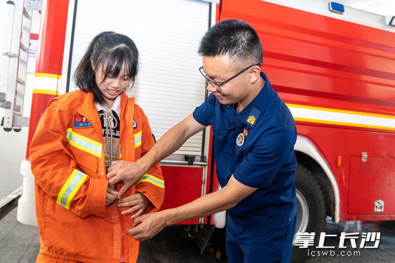 劳动路消防救援站副站长王欢帮助姐姐李晨曦穿消防服。