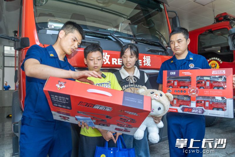 消防战士们为姐弟俩准备了专属消防礼物：4台消防车模型和玩偶。