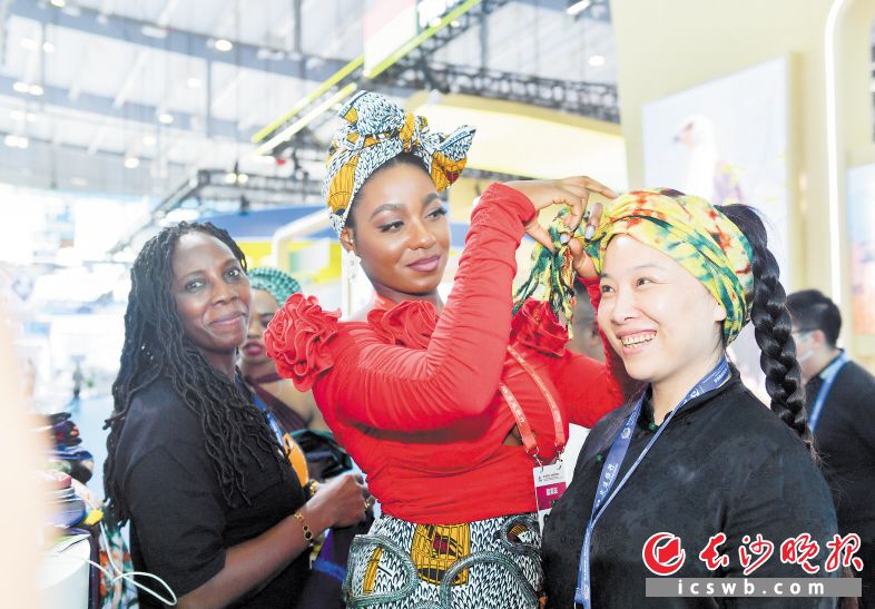 6月30日，第三届中非经贸博览会第二天，一位非洲友人正在给嘉宾系头巾。