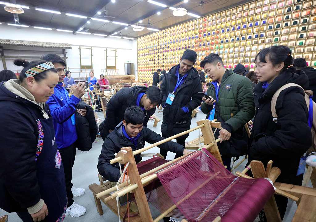 This file photo shows visitors experiencing a local intangible cultural heritage project during their stay in Zhangjiajie, Hunan Province. /CFP