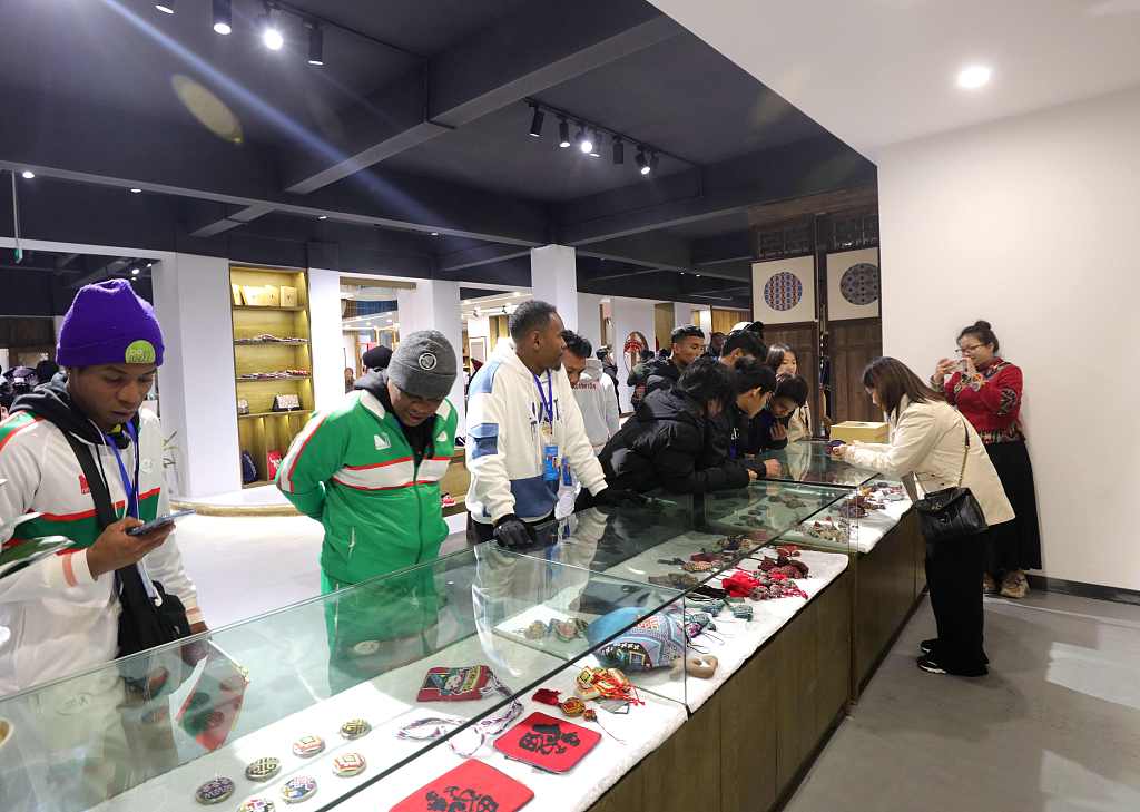 This file photo shows visitors experiencing a local intangible cultural heritage project during their stay in Zhangjiajie, Hunan Province. /CFP