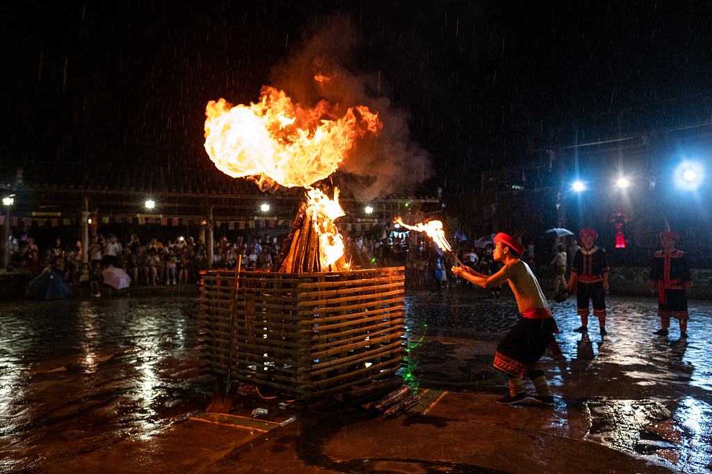A man lights a torch using holy fire from an altar at a Yao village in Nangang, Guangdong Province as a part of the rituals to celebrate the Torch Festival on August 22, 2020. /CFP