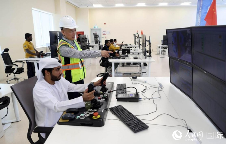马吉德(左2)正在查看堆场自动化轨道吊的工作状态。人民网 纳达尔·达乌德摄