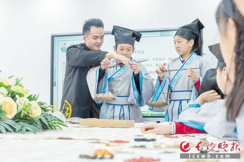 育才学校“小小中医传承人”课堂上,老师指导学生识秤。长沙晚报全媒体记者 周数邑 摄 图片