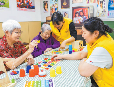 在内蒙古自治区呼和浩特市玉泉区居家社区养老服务标准化示范中心，社区干部在陪老人玩益智游戏。  丁根厚摄（影像中国）