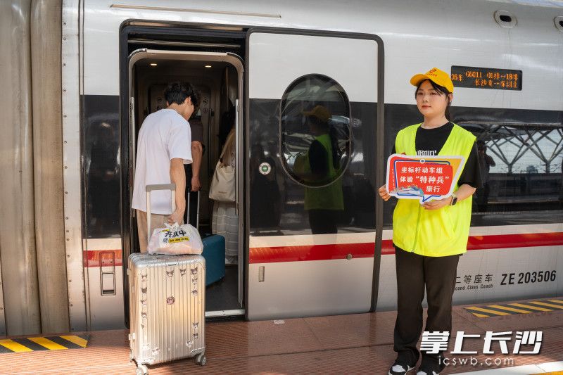 志愿者手持宣传板供乘车旅客打卡纪念。均为全媒体记者 冯启阳摄
