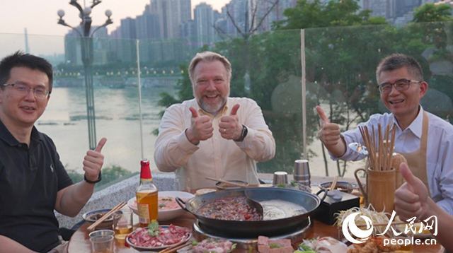 康宁显示科技事业部全球拓建项目总监轲宝华(中)和同事在重庆南滨路吃火锅。人民网记者 苏缨翔摄