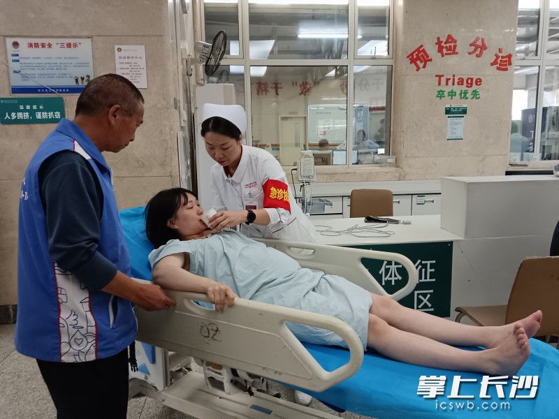 袁亮坤（左）将符苗（中）送至急诊室外科清创室进行检查治疗。