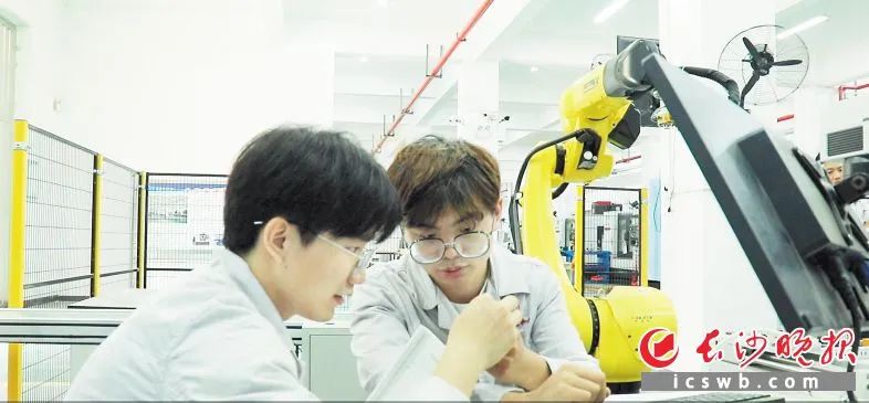 　　黄宇轩（左）与同事在车间研究生产情况。长沙晚报全媒体记者 周斌 摄