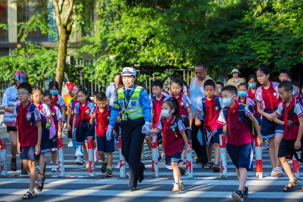 吉首市第八小学上学高峰期，市公安局交警大队“女子护学岗”民警引导学生们安全过马路。
