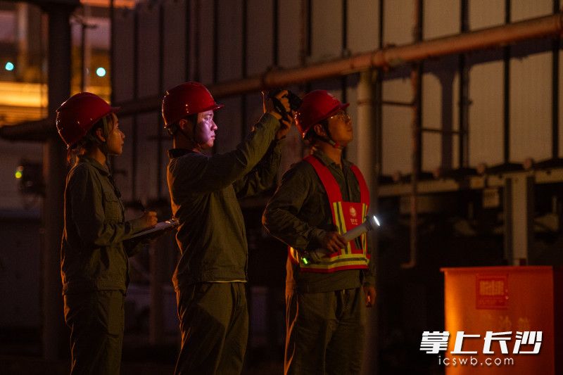 检修人员手拿红外测温仪对重点部位进行照射。