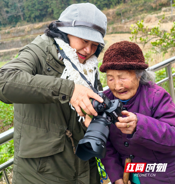 2月3日，湖南省怀化市中方县摄影家协会摄影志愿者在该县铁坡镇江坪村，为103岁的杨仁秀老人拍照，老人欣赏相机里的自己。田文国.jpg