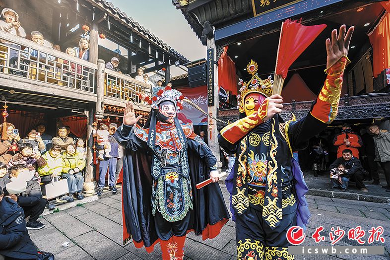 变脸表演中，王启发（左）与师弟亮出“哪吒”和“表情包”等脸谱，获得观众喜爱。