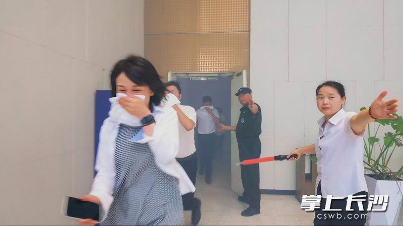 楼道里的人流迅速压低身子，一手捂住口鼻，一手扶着墙壁，沿着疏散指示灯的方向鱼贯而下。 均为全媒体记者 陈飞 摄
