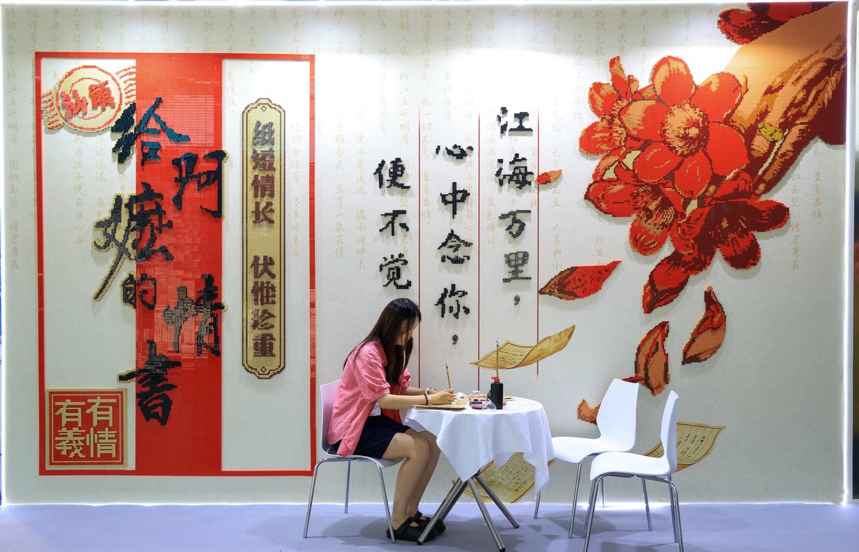 游客在《给阿嬷的情书》电影主题积木打卡墙前体验写批。来源:央视网 游客在《给阿嬷的情书》电影主题积木打卡墙前体验写批。来源:央视网