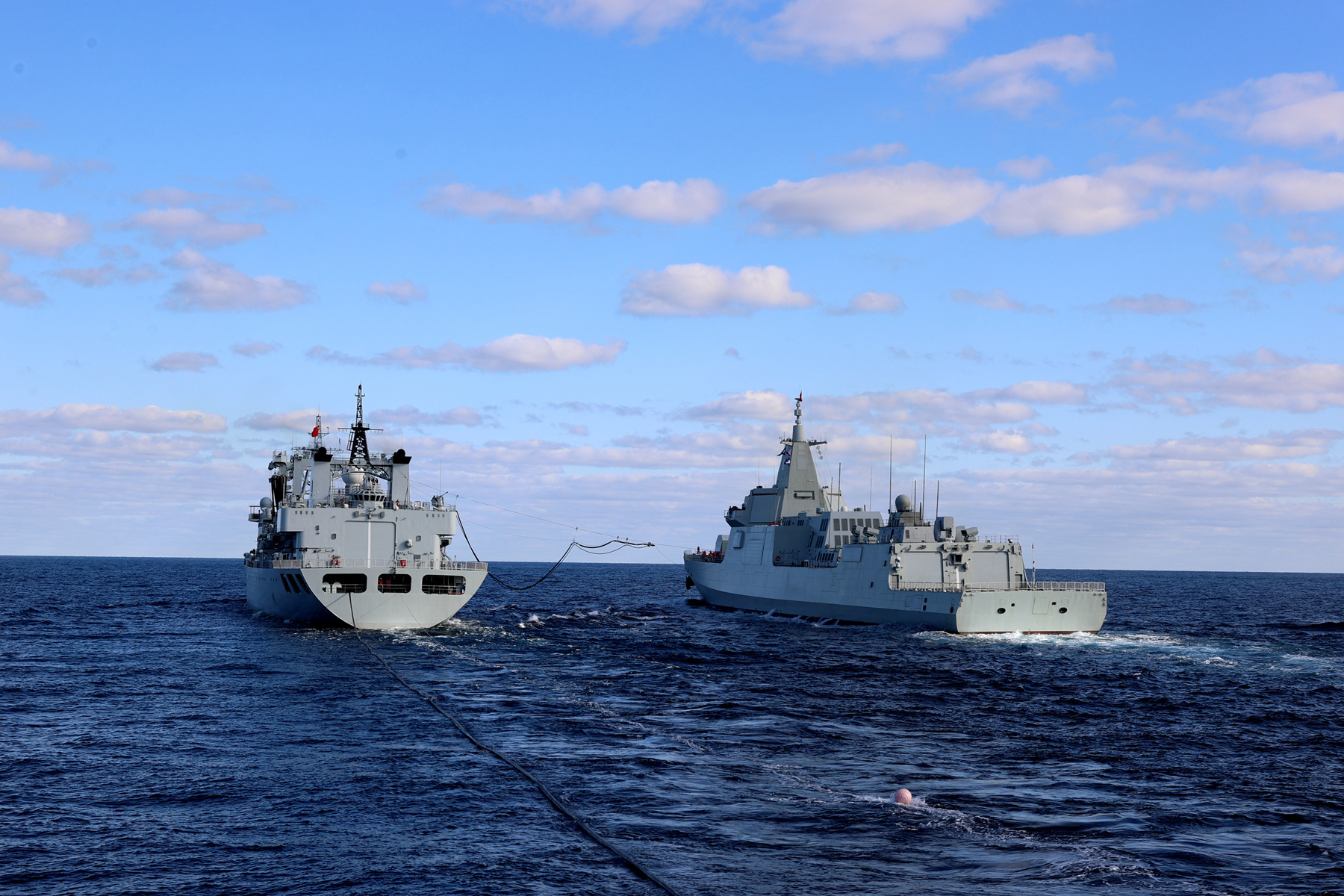 10月13日，参加中俄“海上联合-2021”军事演习的中方水面舰艇在向预定海域航渡。航渡途中，综合补给舰东平湖舰（左）准备向导弹驱逐舰南昌舰（右）进行补给。新华社发（方思航 摄）.JPG