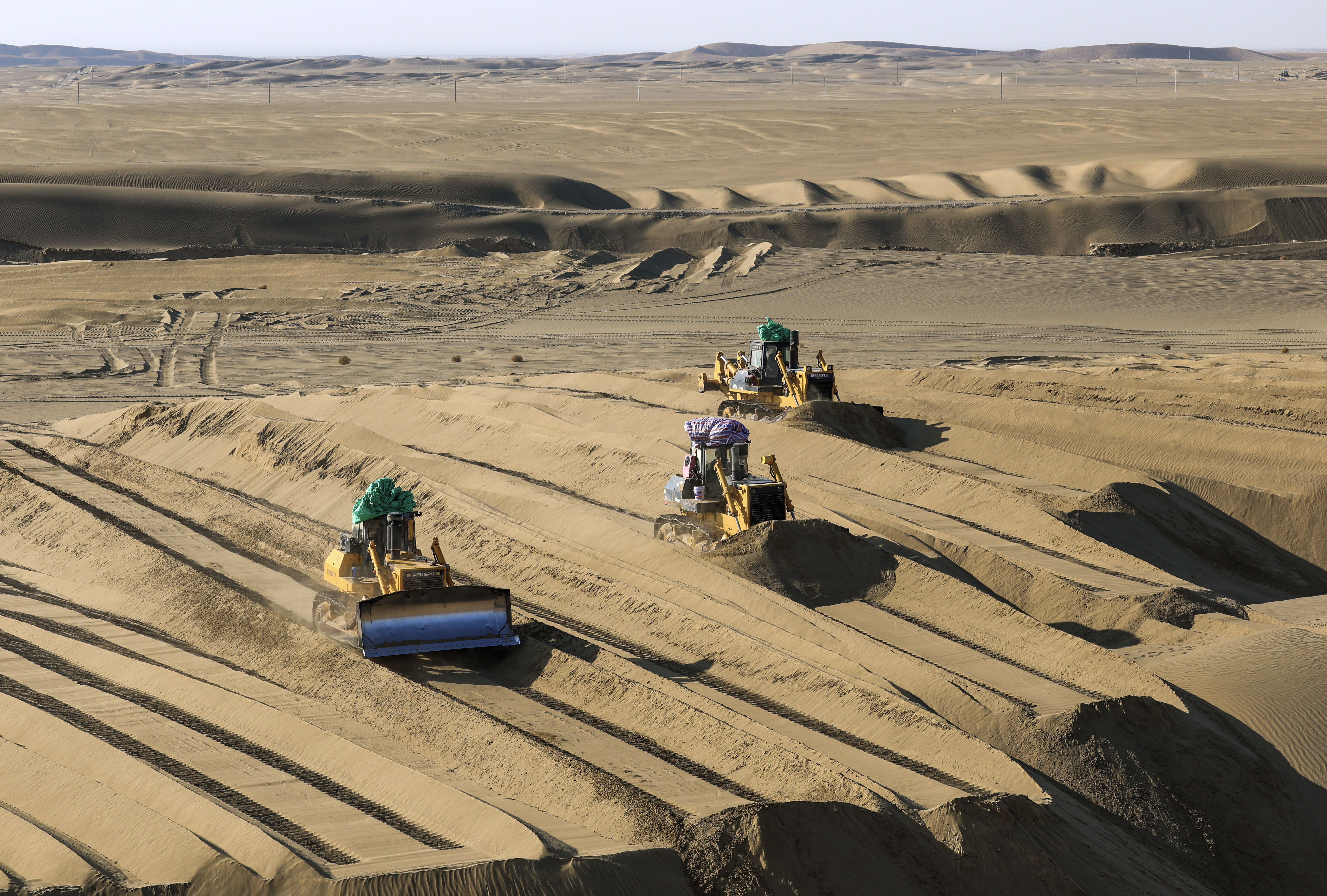 Bulldozers level sandy land in Minfeng County, northwest China's Xinjiang Uygur Autonomous Region, Dec. 2, 2024. (Xinhua/Wang Fei)